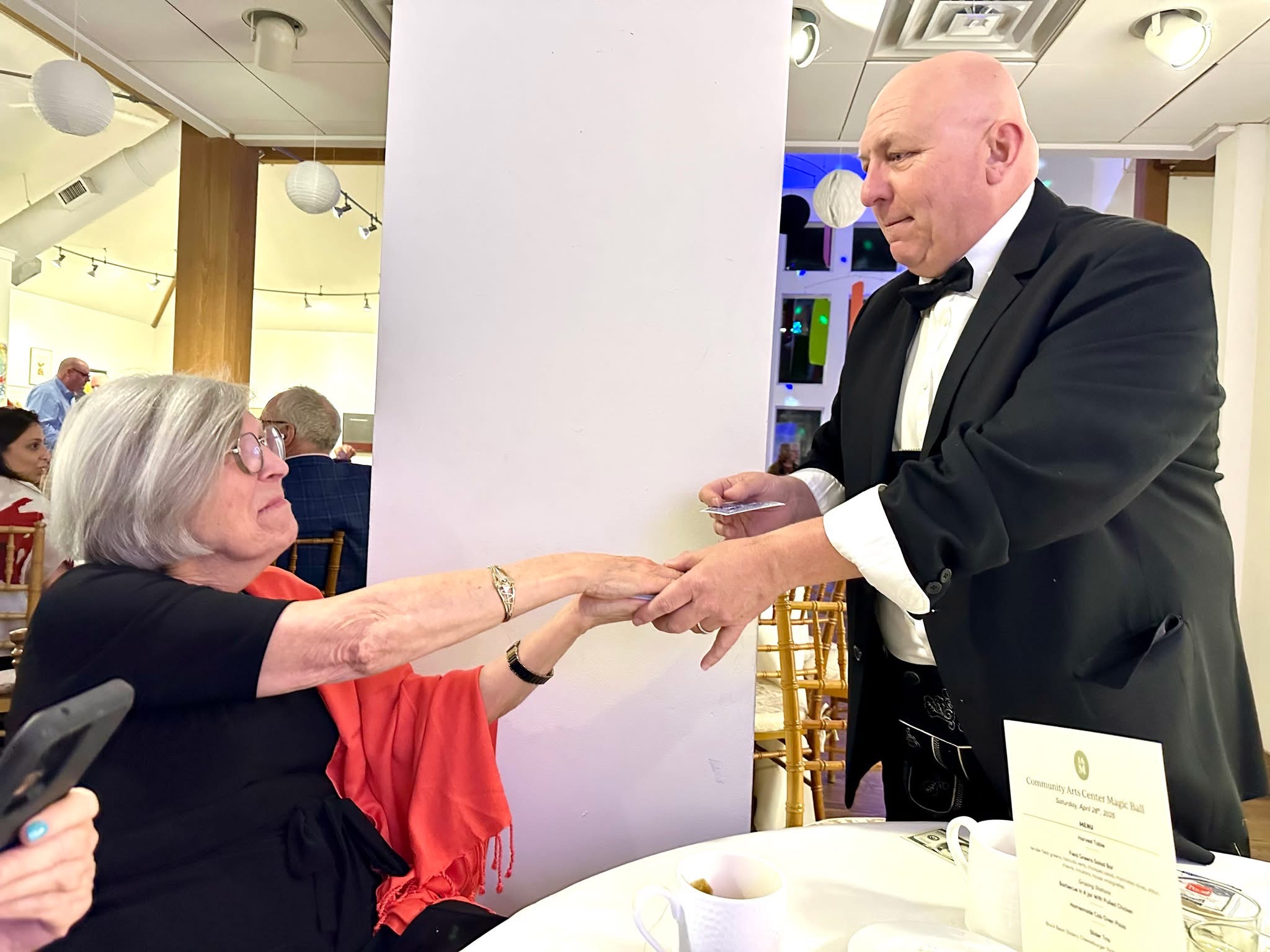 John Kostyal performing close-up card magic for a seated guest